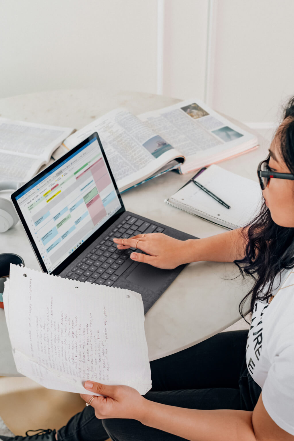 A women looking into the laptop and white paper