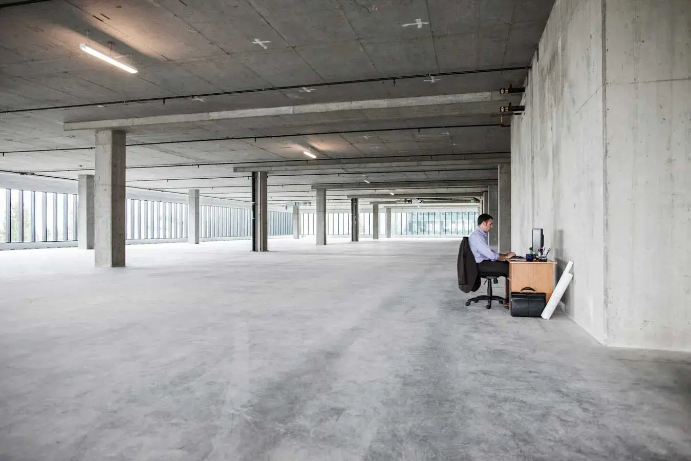 Businessman sitting at a small desk in a large empty raw office space