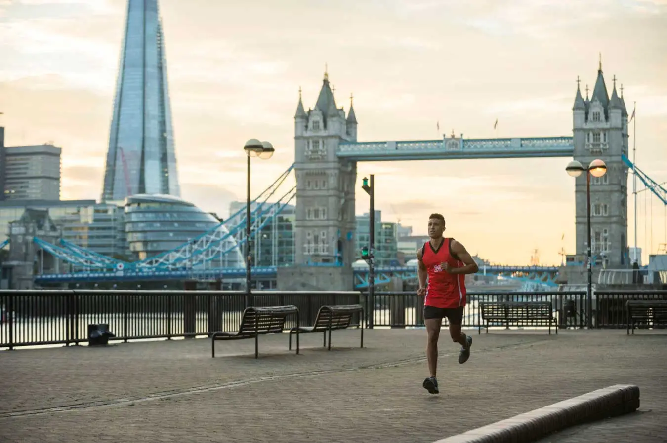Man running by riverside tower bridge Man running by riverside tower bridge
