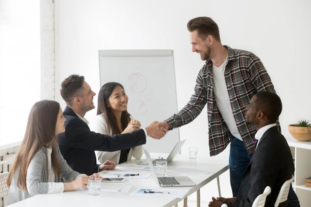 Smiling businessman welcoming new partner group meeting with handshake